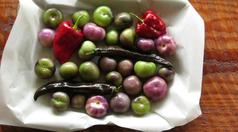 green and purple tomatoes and red bell peppers in white paper